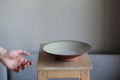 a person reaching out towards a bowl on a stool