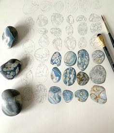 some rocks are sitting on a table next to a pencil and paper with drawings in it