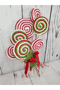 some candy canes are in a vase on a white wooden table with a red bow