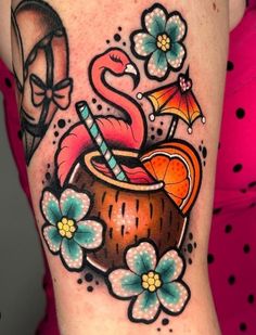 a woman's thigh with an orange juice and flamingos tattoo on her leg