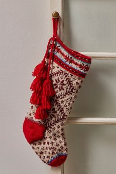 a christmas stocking hanging on the side of a white door with red tassels