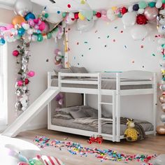 a white bunk bed sitting next to a wall filled with balloons and confetti