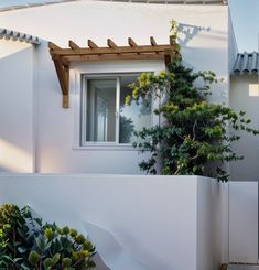 a white house with a small tree in front of it and an awning over the door