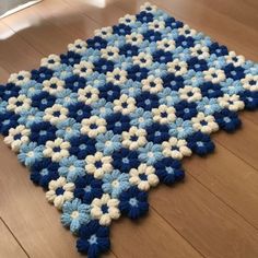 a blue and white crocheted rug is on the floor in front of a wooden floor