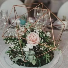 a white table topped with a vase filled with flowers and greenery next to a candle holder