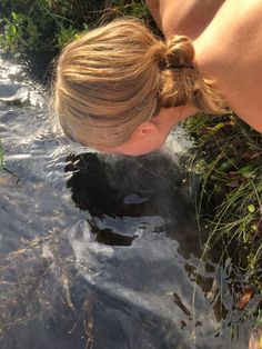 a woman bending over to look at the water that is running through her body,