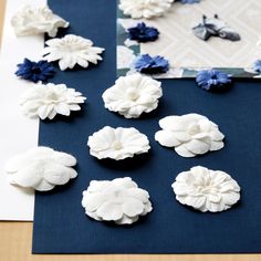 several white and blue flowers are laying on a table next to a piece of paper