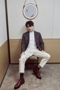 a man sitting on a chair in front of a wall with a mirror above him