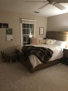 a bedroom with a bed, dresser and ceiling fan in the corner next to an open window