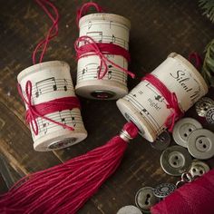 three spools of string tied together with buttons and thread on the table next to them