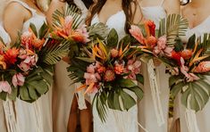 a group of bridesmaids in white dresses holding bouquets with tropical leaves and flowers