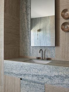 a bathroom sink sitting under a mirror next to a faucet mounted on a wall