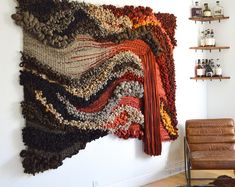 a wall hanging made out of crocheted yarns and leather chairs in a living room