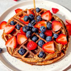 a waffle topped with strawberries and blueberries on top of a white plate