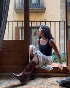 a woman sitting on a window sill looking out