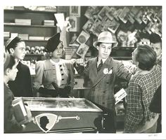 an old black and white photo of people in a store looking at items on display