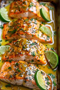 three salmon fillets with limes and seasonings on a baking sheet