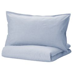 a blue pillow sitting on top of a bed next to a white pillow cover and two pillows