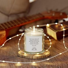 a candle sitting on top of a wooden table next to a string of lights and a guitar