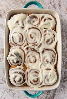 a pan filled with cinnamon rolls covered in icing