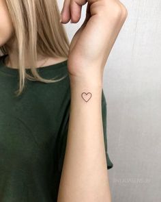 a woman with a small heart tattoo on her arm