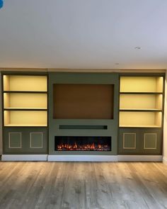 an empty living room with a fireplace and built in bookshelves