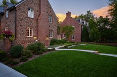 a large brick house sitting on top of a lush green field