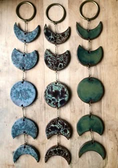 several different types of moon and crescent shaped pendants on a wooden surface with metal rings