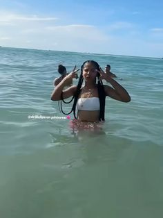 a woman standing in the ocean with her hair tied back