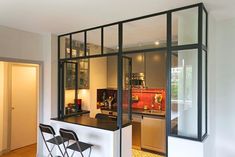 an open kitchen and dining area with chairs in the center, is seen through glass partitions