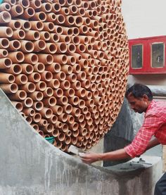 a man is working on a large stack of clay pipes that are stacked high in the air