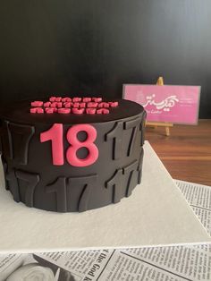 a birthday cake with the number eighteen on it sitting on top of a newspaper page