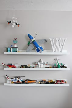 two white shelves with toy cars and airplanes on them