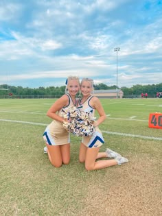 two cheerleaders pose for a photo on the field