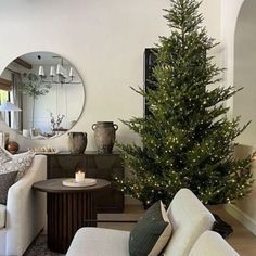 a living room filled with furniture and a christmas tree in front of a round mirror