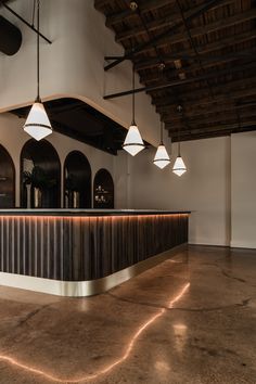 an empty bar with three lights hanging from it's ceiling in a large room