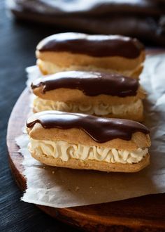 three pastries with chocolate and cream frosting sitting on top of wax paper next to each other