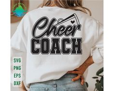 a woman wearing a white sweatshirt with the words cheer coach printed on it in black