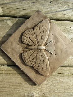 a square shaped tile with a four leaf clover on it's center, sitting on a wooden surface