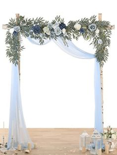 a white and blue wedding arch decorated with flowers, greenery and candles on a wooden floor