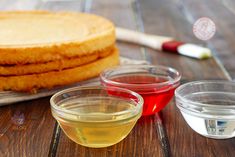 three bowls with different colored liquids on a wooden table next to some toasted bread