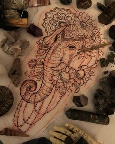 an elephant with flowers on it's head surrounded by rocks and other items that include crystals