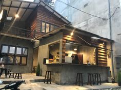 an outdoor bar with stools and tables in front of a building that has stairs leading up to it