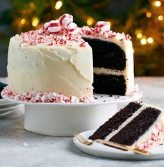 a cake with white frosting and candy canes on it sitting next to a plate