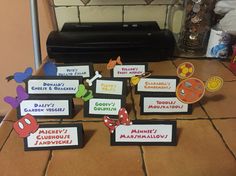 there are many different name tags on the counter top with mickey mouse and minnie mouse magnets