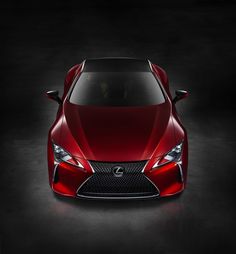 the front end of a red sports car in a dark room with its lights on