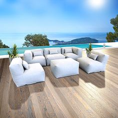 a large white couch sitting on top of a wooden floor next to an ocean view