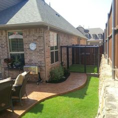 a brick house with a patio and fenced in area next to the yard is surrounded by green grass