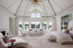 a large bedroom with white walls and furniture in the center, along with a chandelier hanging from the ceiling