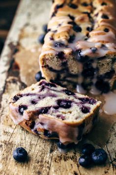 a loaf of blueberry bread sitting on top of a wooden cutting board